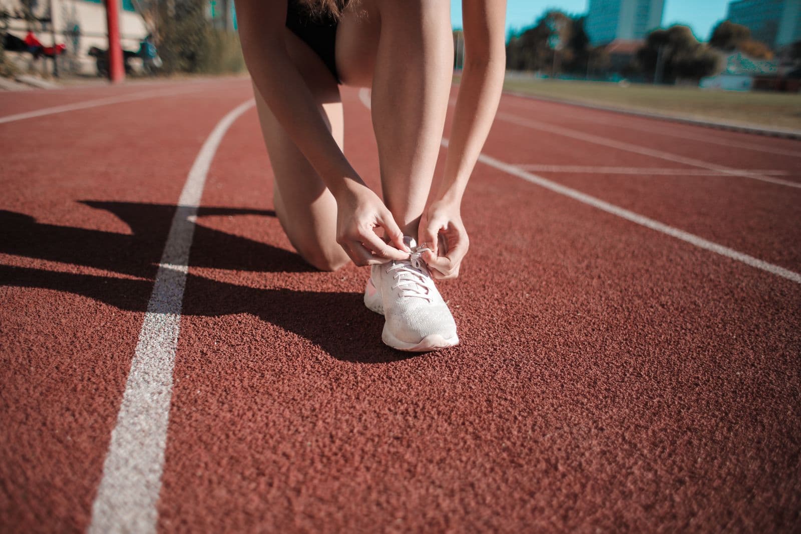 Coureuse nouant ses lacets sur une piste d’athlétisme