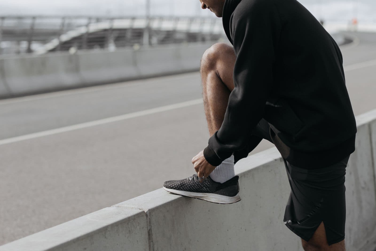 Coureur ajustant sa chaussure sur un muret en ville