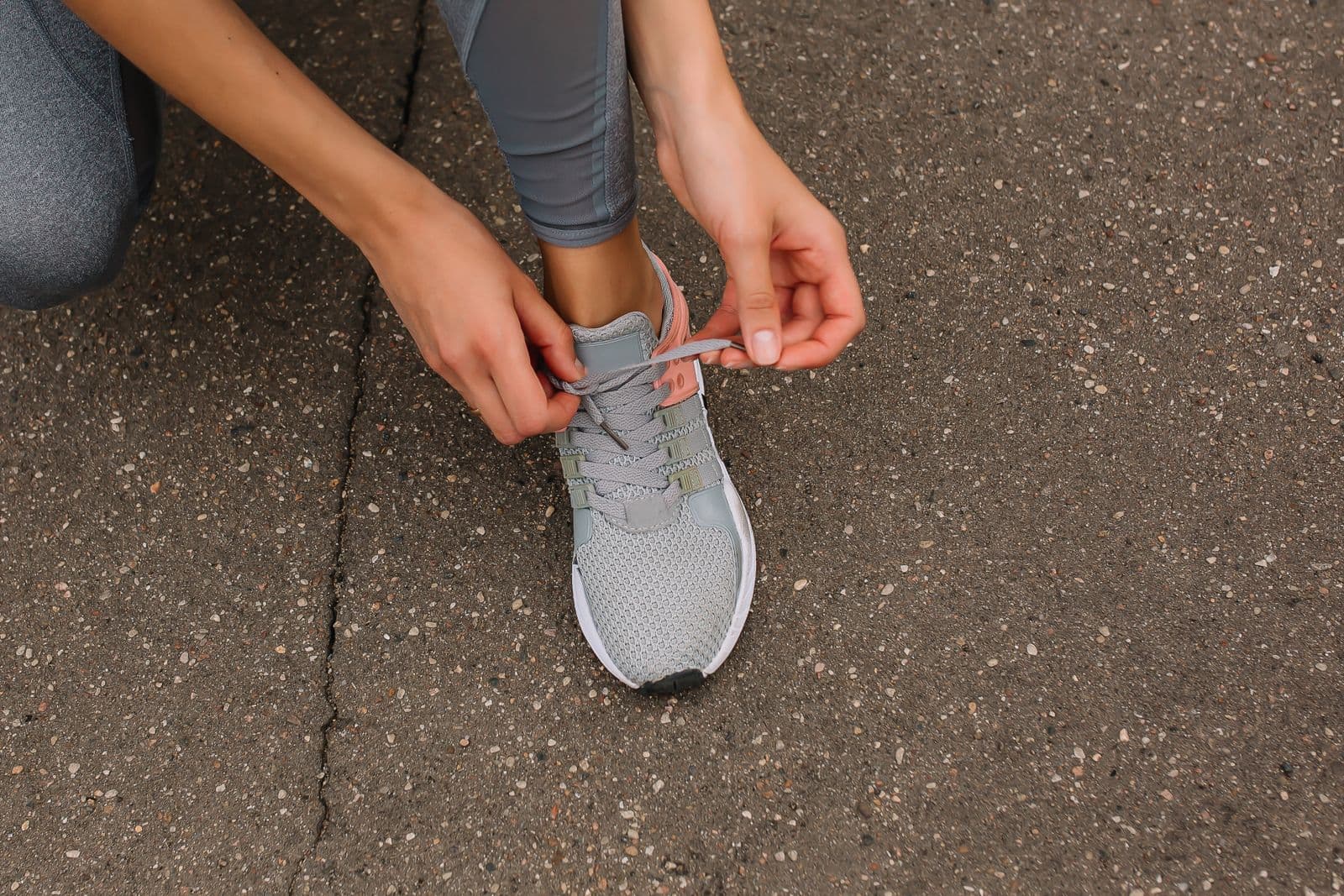 Coureuse laçant sa chaussure de running sur le bitume